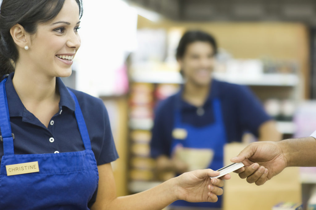 Closeup of a hand giving female employee loyalty card in superma